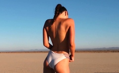Curvy petite brunette strips at a beach